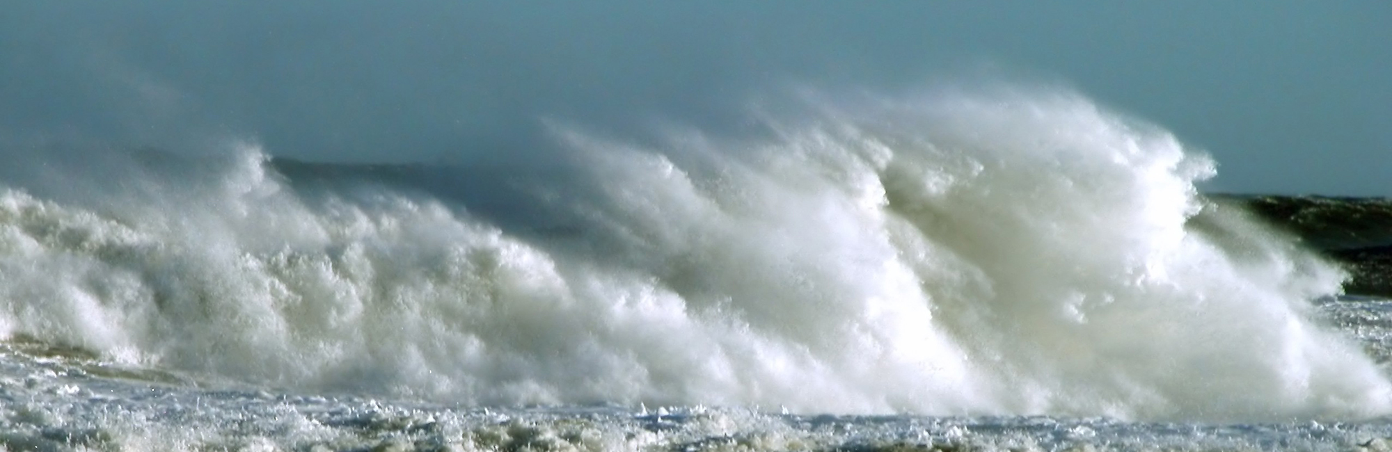 Photograph showing the sea spray above some waves.