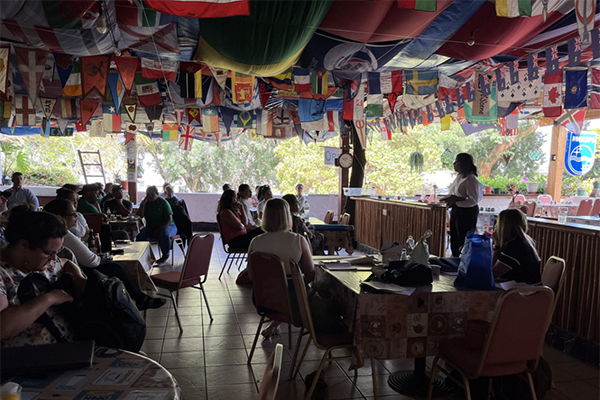 Photograph of participants at the workshop in St Helena. Participants are seated around tables and looking at a presenter at the side of the room